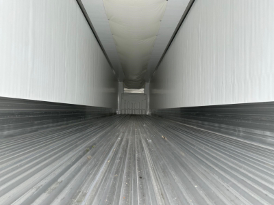 Trailer interior long box with ribbed metal floor, white walls, and ceiling insulation showing a rear end; empty cargo area of a Utility 3000R trailer.