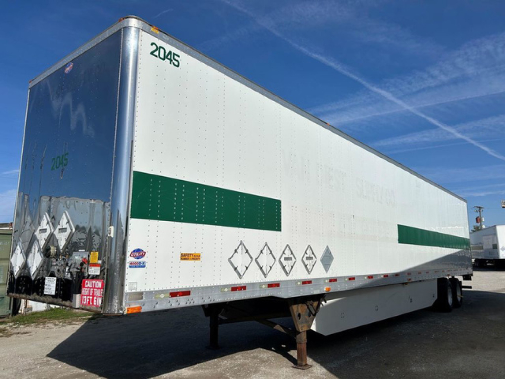 Trailer side view showing a dry van trailer with white exterior, green reflective bands, and safety placards. VIN and stock number not visible on the trailer itself.