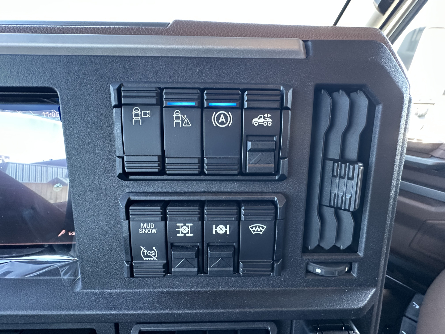 Dashboard control panel with multiple switches in a Mack PR64T64 truck cab showing various icons including trailer stability, braking, and climate controls.