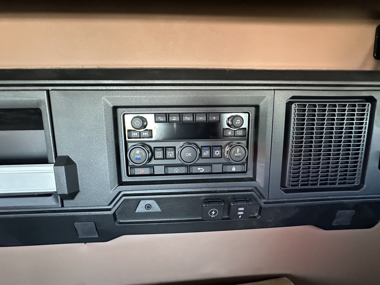 Dashboard panel with control cluster and vents in a Mack truck cab showing various buttons and knobs.