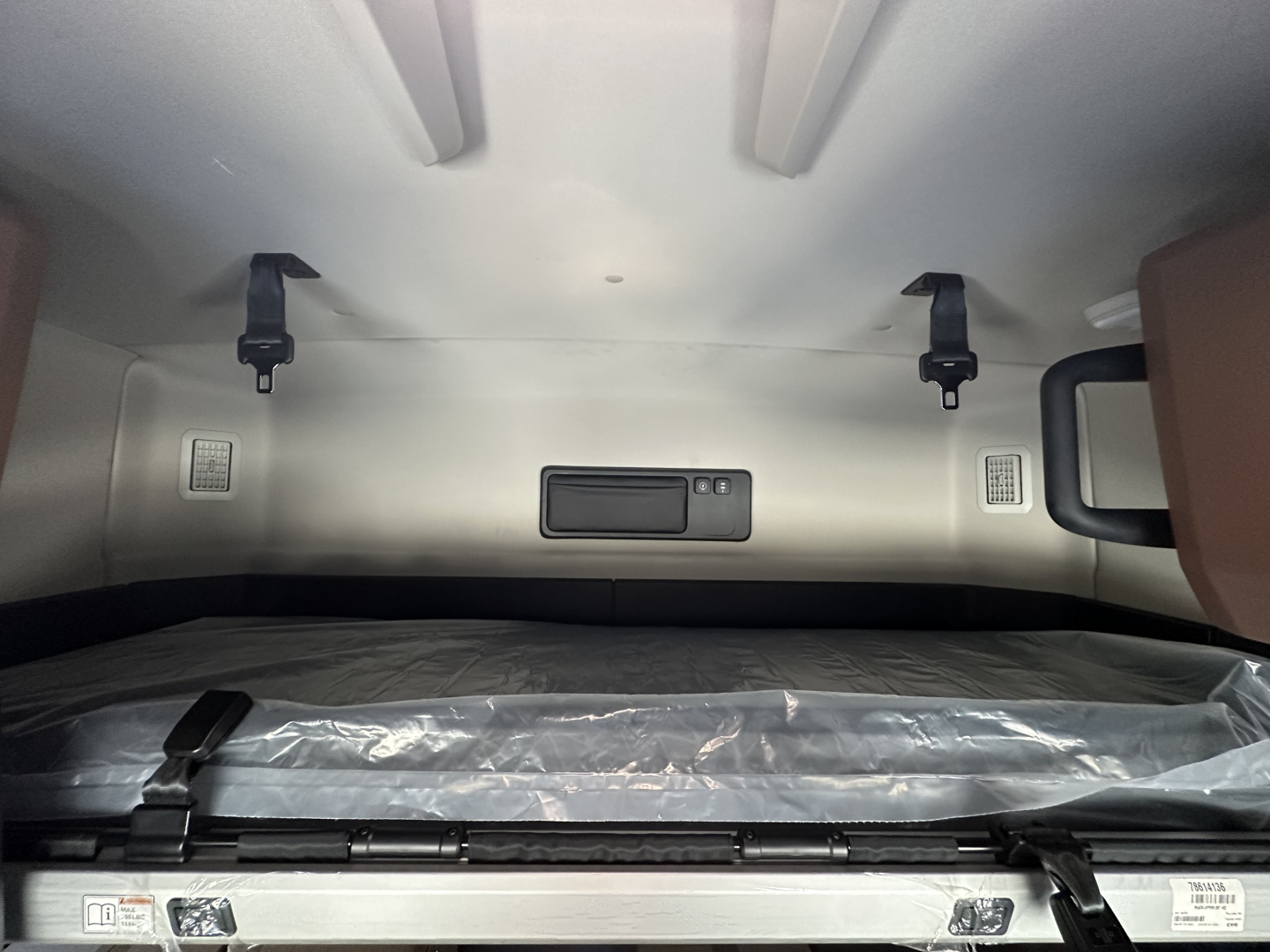 Interior sleeper cab storage area with a fixed shelf and tie-downs in a Mack PR64T64.