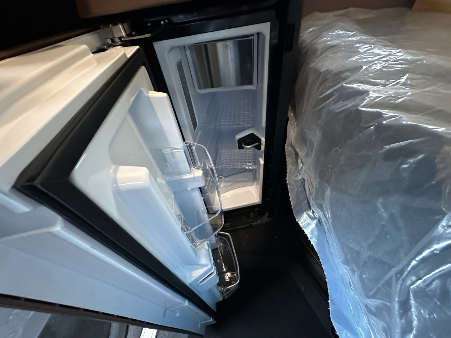 Frontal view of a new Mack PR64T64 sleeper cab interior showing an open refrigerator/freezer compartment and door shelves.