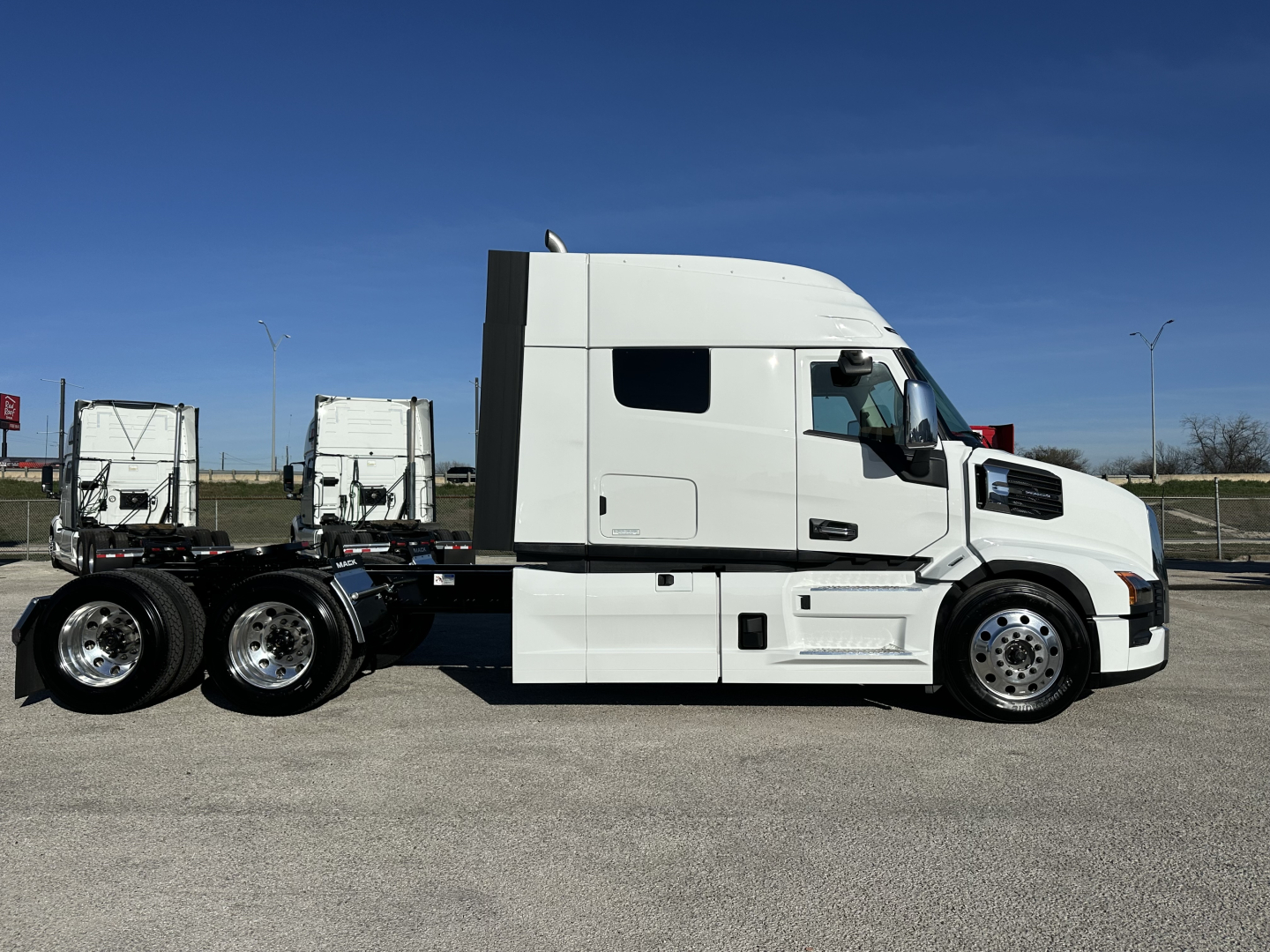 White Mack PR64T64 truck cab and chassis side view showing sleeper cab and dual rear axles under clear sky