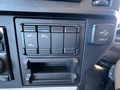 Truck interior dash showing switch panel with four vertical rocker switches and a USB-C port labeled in-cab storage area