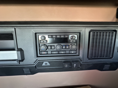 Dashboard panel with control cluster and vents in a Mack truck cab showing various buttons and knobs.