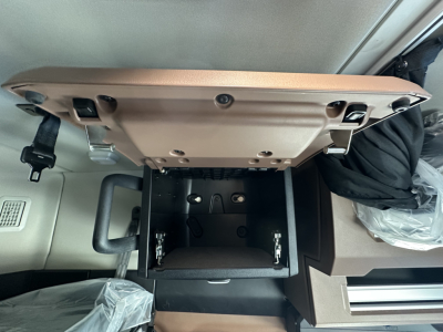 Cab interior of a 2026 Mack PR64T64 showing an open center storage compartment with folded armrest and exposed mounting brackets.