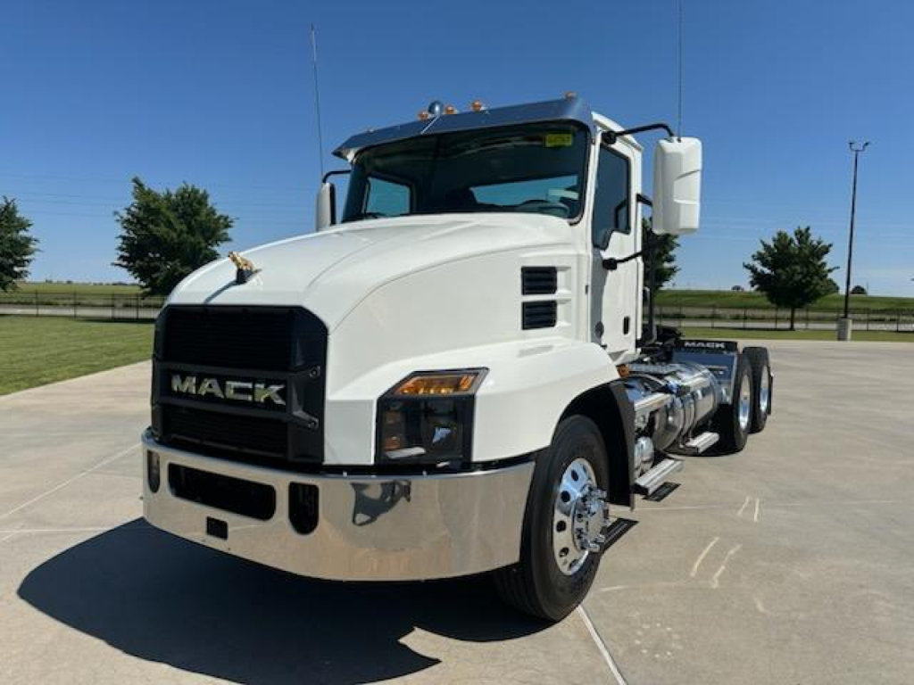 Mack AN64T conventional daycab truck in white, front angle view showing large black grille, chrome bumper, dual rear wheels, and side fuel tanks with steps.
