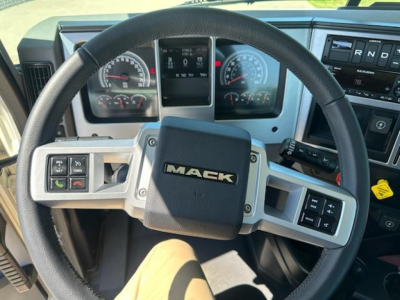 Mack AN64T truck cockpit showing steering wheel with Mack logo, instrument cluster, and control buttons on the steering spokes.