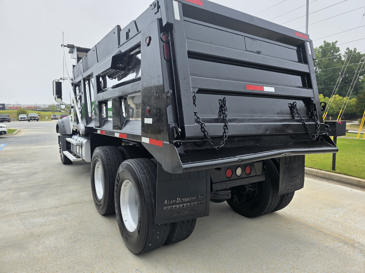 Dump truck rear view showing Mack GRANITE dump body with black paint, dual rear axles, chains on tailgate, rear lights, and mud flaps.