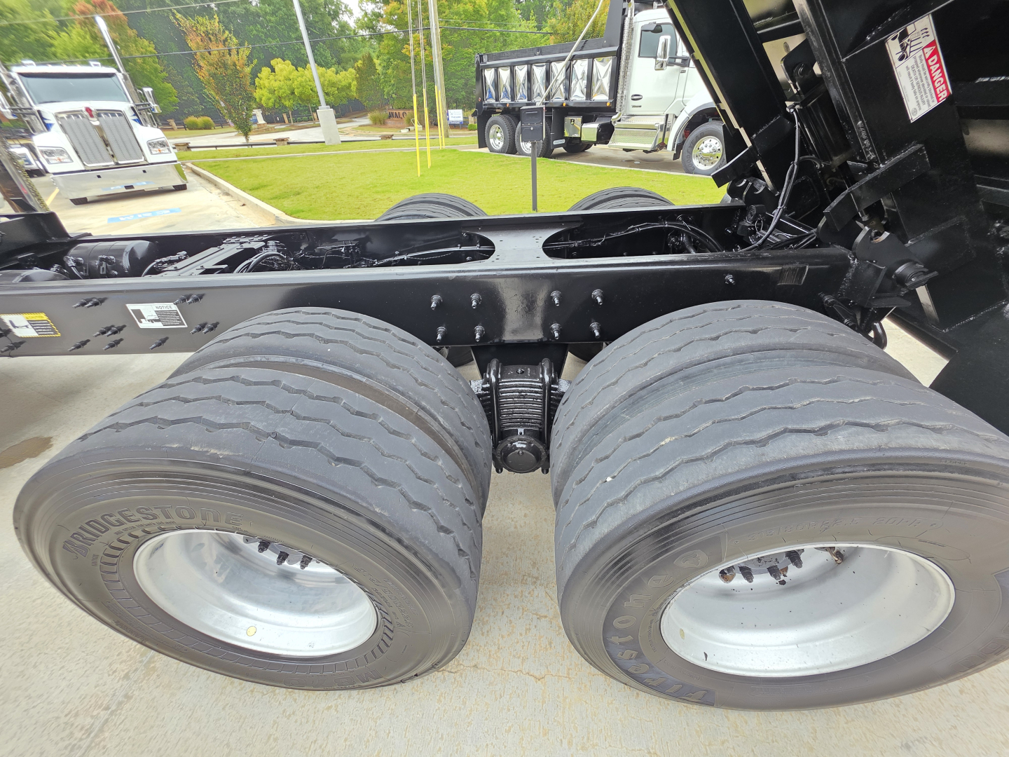 Mack Granit? granite dump truck chassis showing dual rear axles with large dual tires and suspension, undercarriage view.
