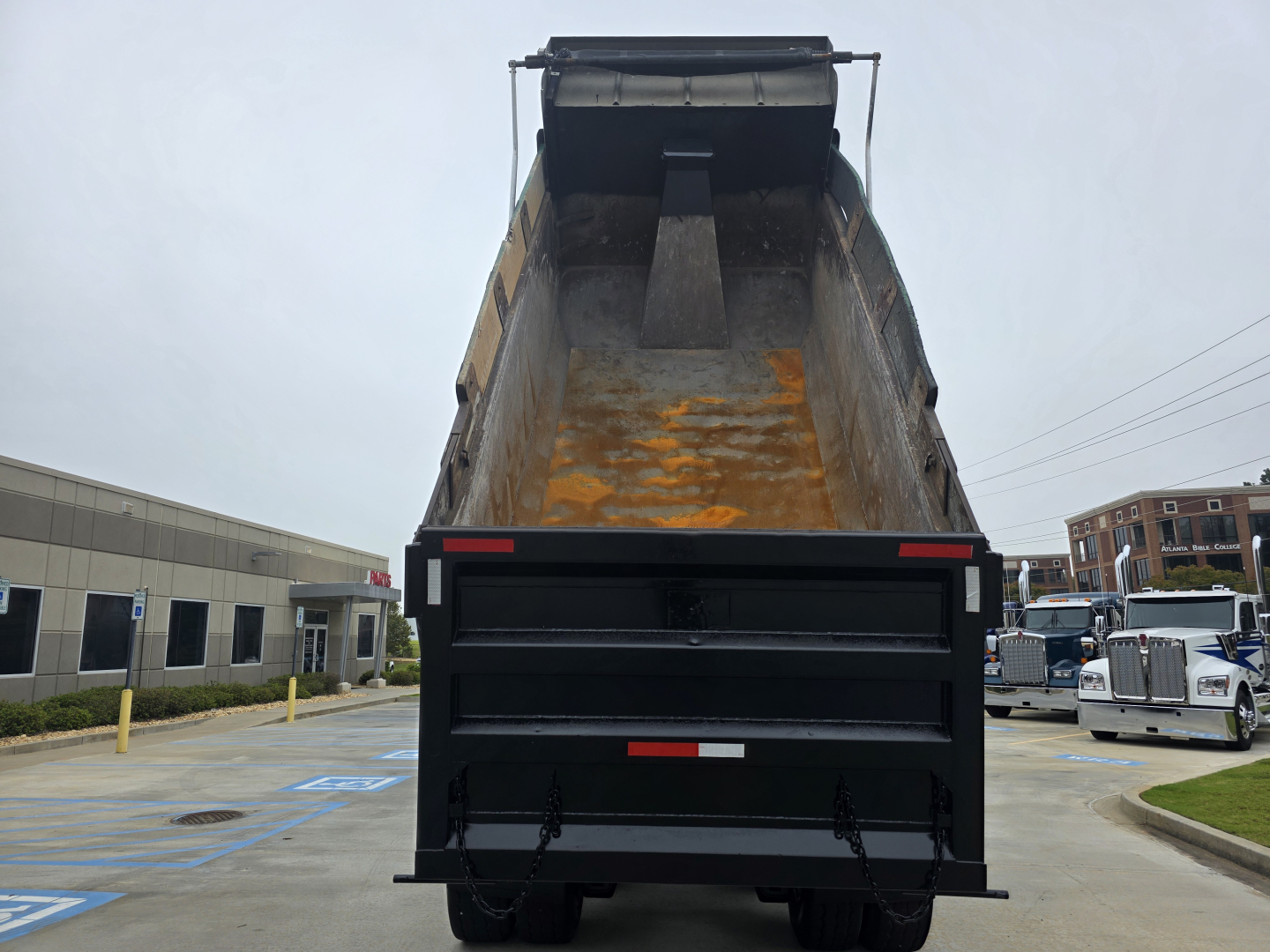 Truck bed of a Mack GRANITE dump truck showing empty bed with some rust stains and rear tailgate open.