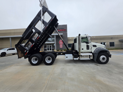 Dump truck side view showing raised bed on a 2022 Mack Granite with white cab and black dump body.