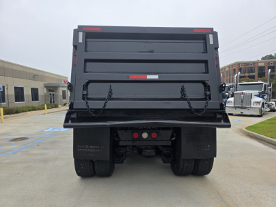Dump truck bed rear view showing Mack Granite dump body with chained tailgate and taillights.
