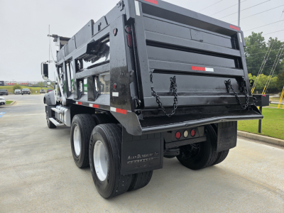 Dump truck rear view showing Mack GRANITE dump body with black paint, dual rear axles, chains on tailgate, rear lights, and mud flaps.