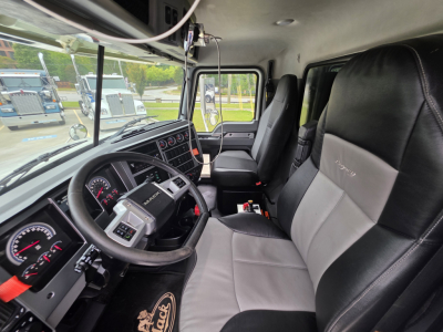 Cab interior of a 2022 Mack GRANITE dump truck showing steering wheel, dashboard, driver and passenger seats, and window view.