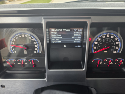Dashboard view of a Mack Granite truck showing vehicle total readouts on center screen and analog gauges for speed and RPM.