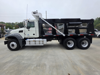 Dump truck side view showing Mack Granite with black dump body and chrome fuel tanks, VIN plate may be visible.