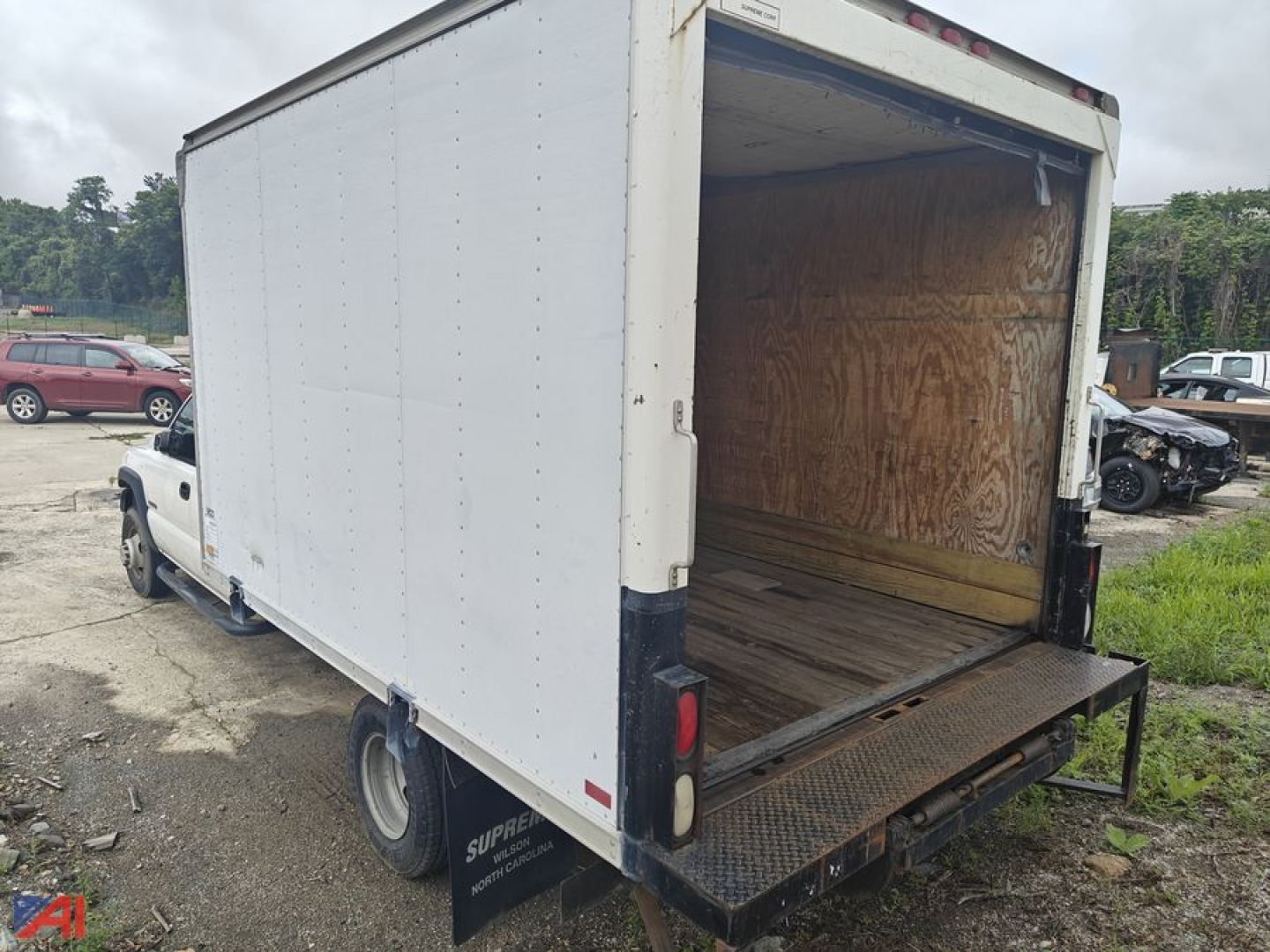 Box truck cargo area showing empty wooden interior, rear ramp lowered, white box body on Chevrolet Silverado 3500 chassis.