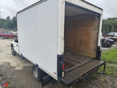 Box truck cargo area showing empty wooden interior, rear ramp lowered, white box body on Chevrolet Silverado 3500 chassis.