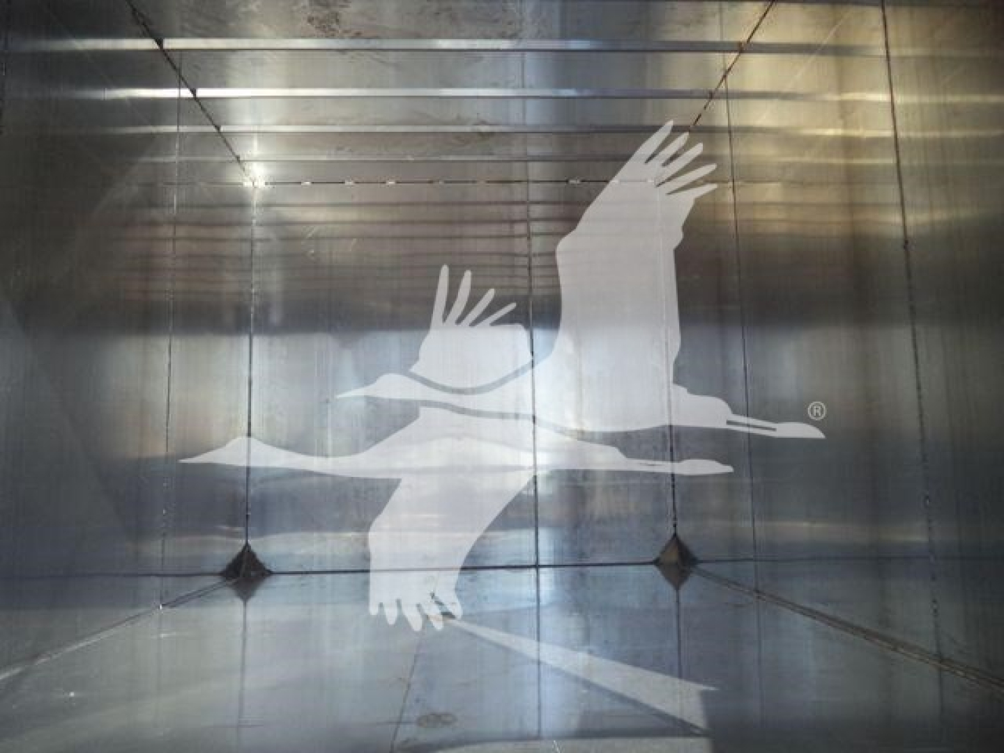Isuzu truck chassis interior showing overhead lights and a large logo of flying birds on a metal wall
