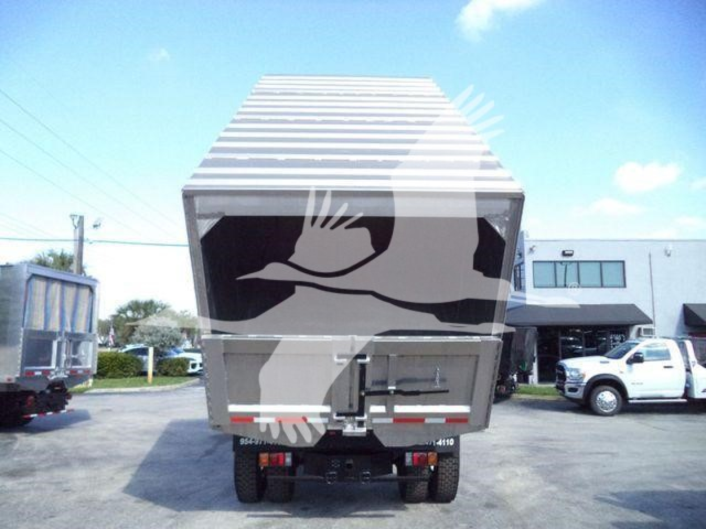 Isuzu forward-view of a dump truck or chipper unit bed with raised cargo container and rear doors visible.