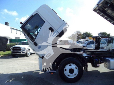 Isuzu FTR truck cab tilted up showing front wheel and chassis with blue sky