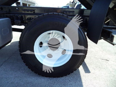 Isuzu FTR truck wheel and tire assembly showing white rim and black tire with fender area and chassis components.