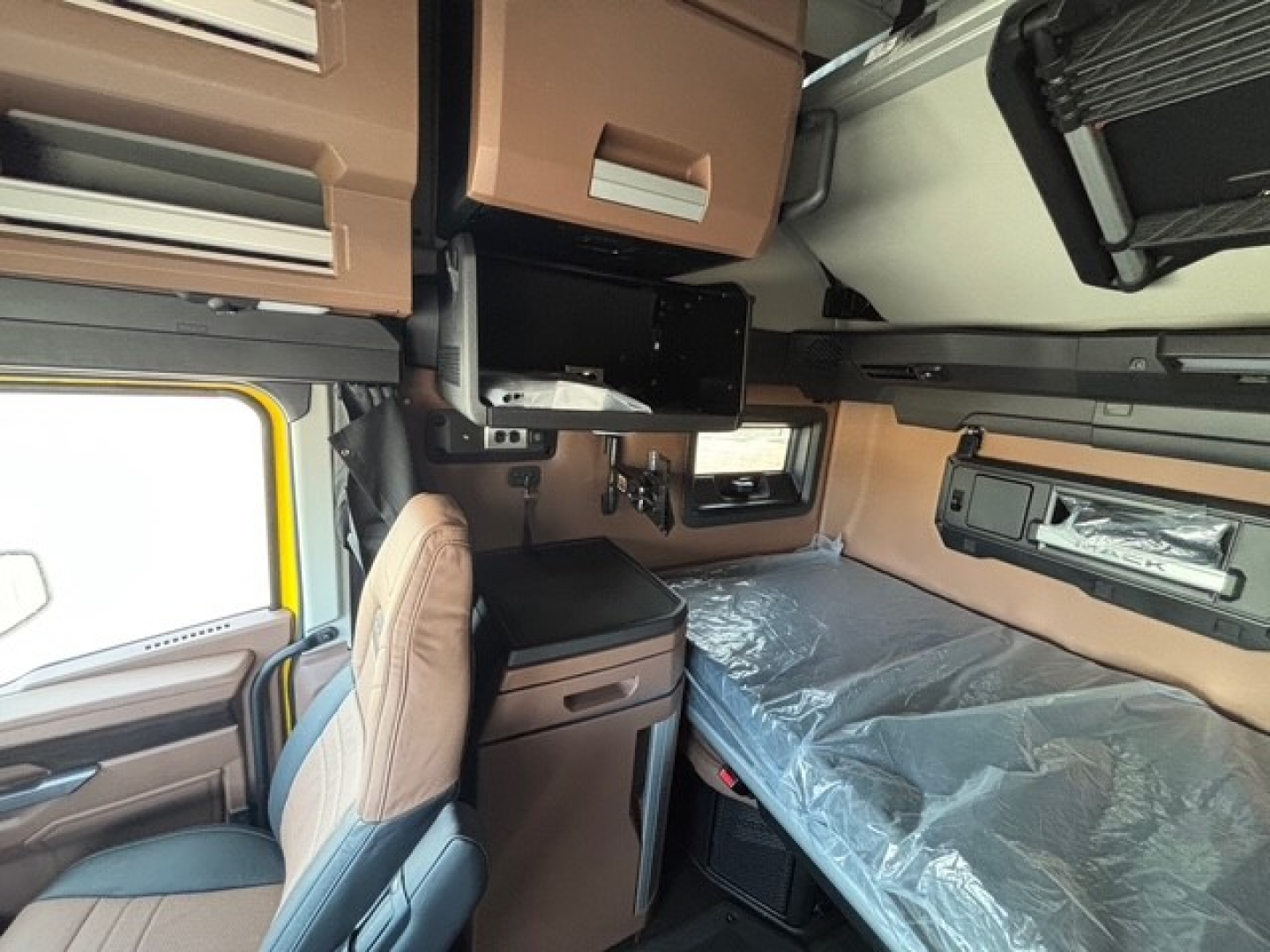 Cab interior of a 2026 Mack PR64T76H truck showing sleeper area with bunk bed, overhead cabinets, and seating. Text not visible.