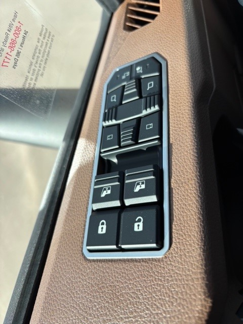 Truck interior panel with window/lock switches and mirror controls; brown textured trim; vertical arrangement of black buttons with white icons.