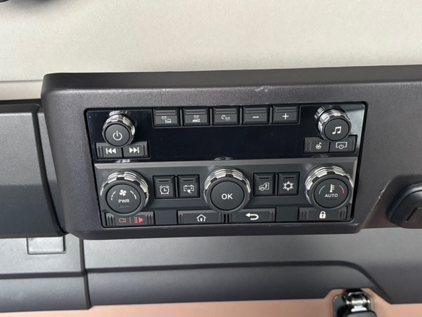 Dashboard control panel with multiple buttons and knobs in a Mack PR64T76H truck cab showing climate and media controls