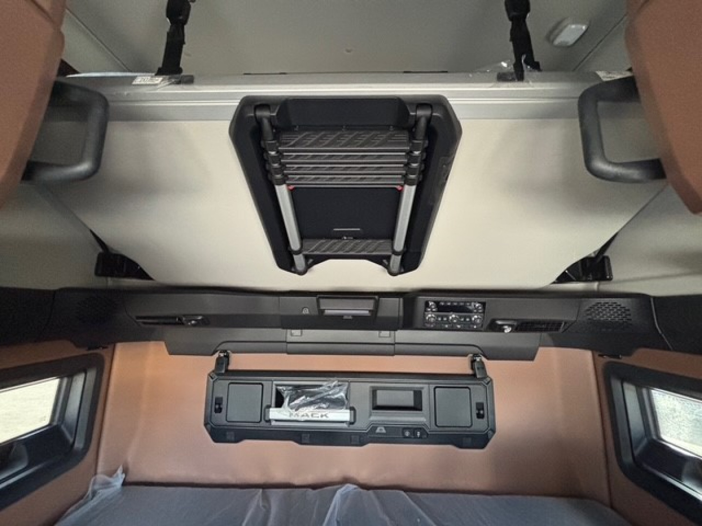 Mack PR64T76H sleeper cab interior showing overhead bunk area with sunshield and overhead controls.