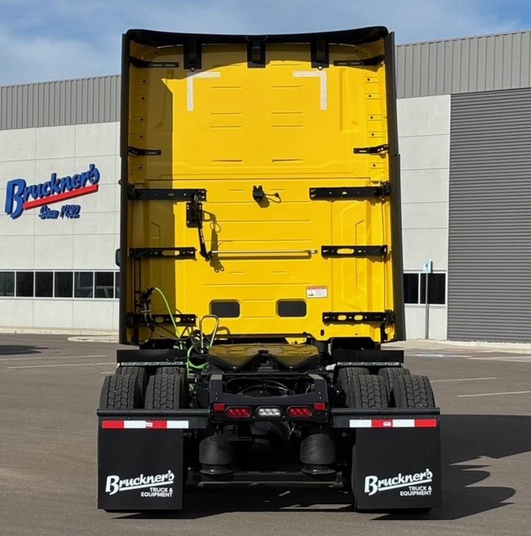 Rear view of a bright yellow Mack PR64T76H tractor with black chassis and mud flaps showing Bruckner's branding and stock equipment.