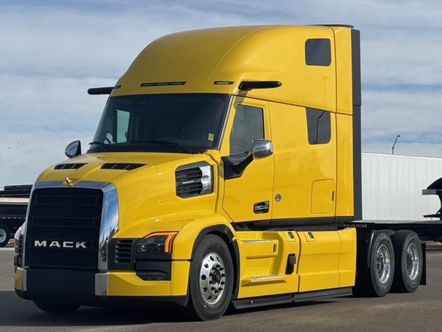 Mack PR64T76H conventional sleeper truck in yellow side view showing cab and front grille with Mack logo and chrome accents.