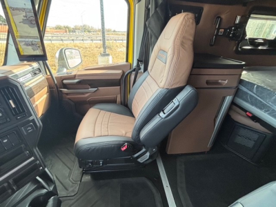 Cab interior of a new Mack PR64T76H truck showing driver seat, dashboard, and sleeper area with beige and black trim.