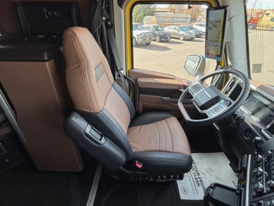 Truck cab interior showing steering wheel and driver seat in a Mack PR64T76H sleeper truck.