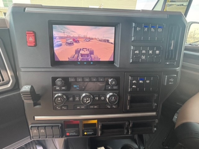 Mack PR64T76H dash panel with touchscreen display and rows of control switches, climate controls, and storage compartments.