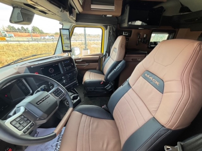 Cab interior of new 2026 Mack PR64T76H showing dashboard, steering wheel, and tan leather seats with Mack branding.