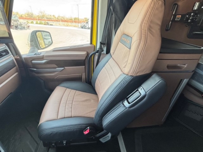 Cab interior of 2026 Mack PR64T76H showing tan and black driver seat, steering wheel, and dashboard area.