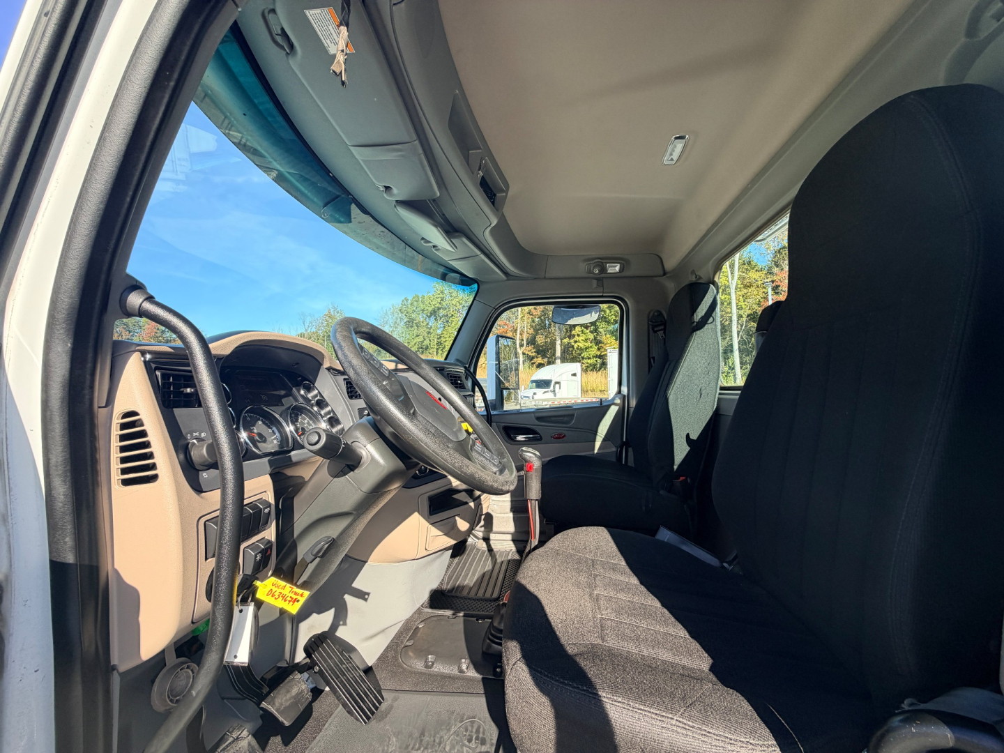 Truck cabin interior of a 2020 Peterbilt 567 showing the steering wheel, dashboard, pedals, and driver seat.