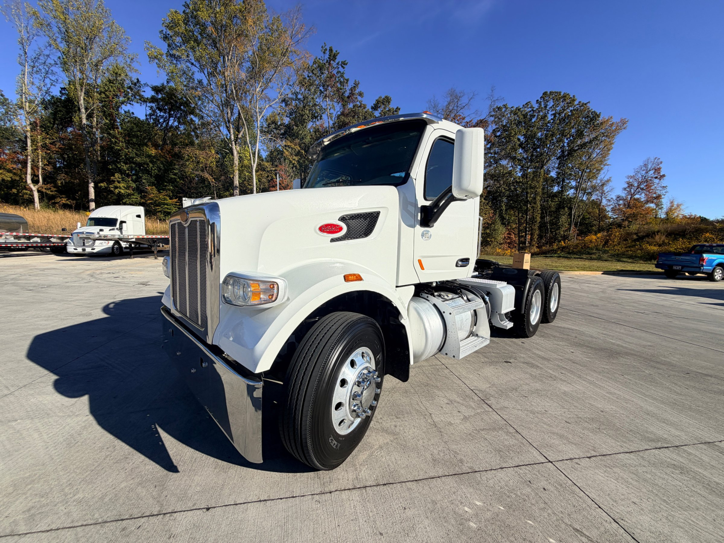 Peterbilt 567 conventional daycab truck in white, front angle view showing front grille, headlights, and cab; 6x2 dual rear axle configuration.