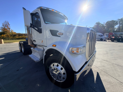 Peterbilt 567 conventional daycab truck showing front grille, bumper, and wheel with chrome hubcap.