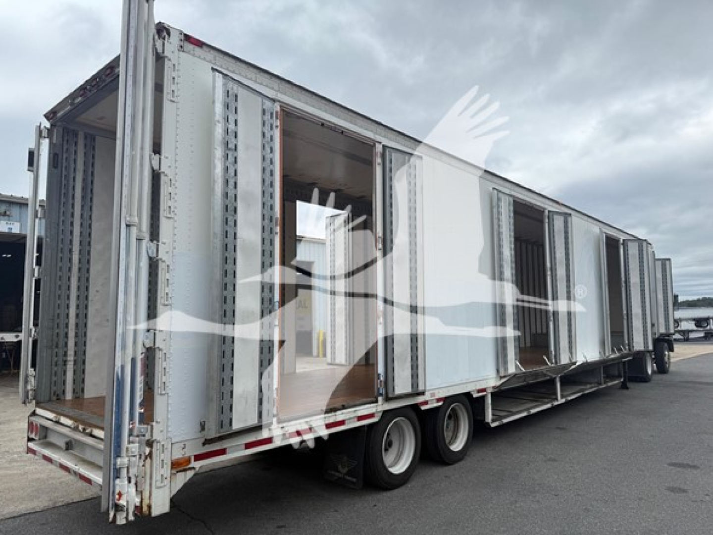 Trailer side view showing moving van trailer with open rear doors, aluminum chassis, triple-axle setup and ramp access, Kentucky Trailer logo watermark