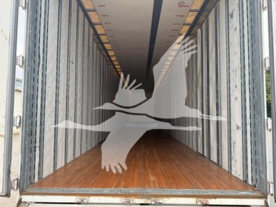 Trailer interior view of a Kentucky Moving Van trailer with wooden floor and metallic sidewalls, open rear doors, long empty cargo bay.