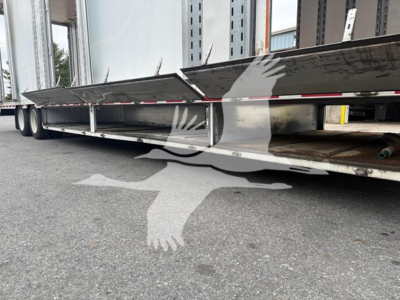 Trailer underside of a moving van with side skirts, metal frame, and wheels visible under the trailer.
