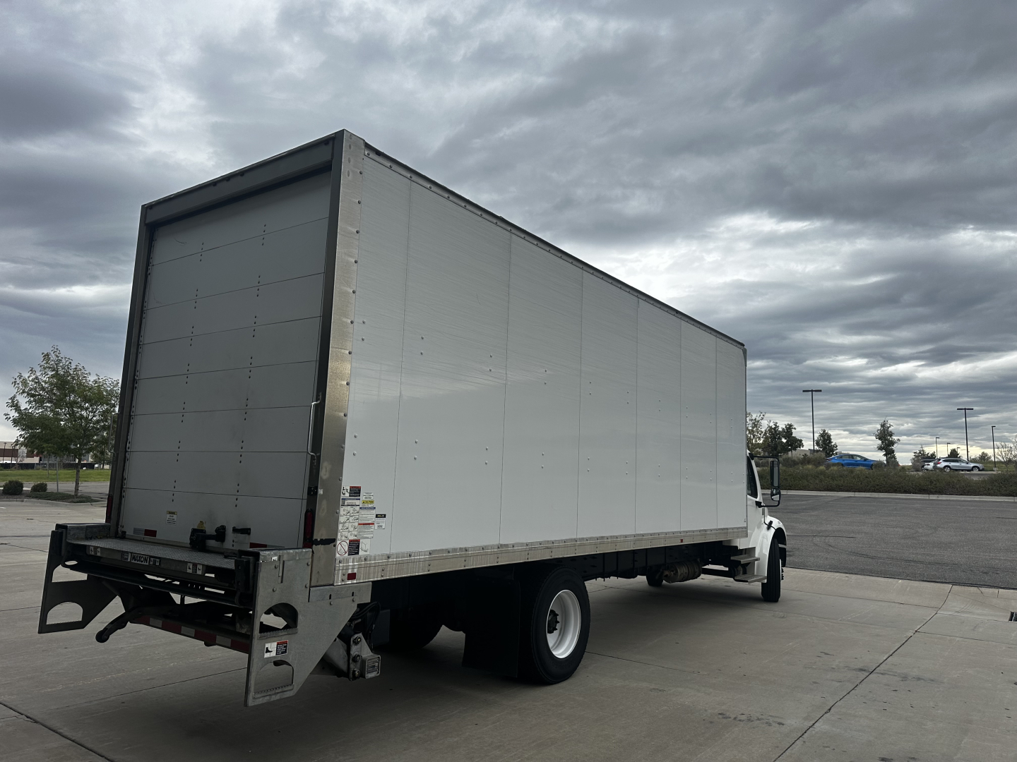 Box truck from rear-left view showing cargo box and cab of a Freightliner M2-106 with aluminum box.