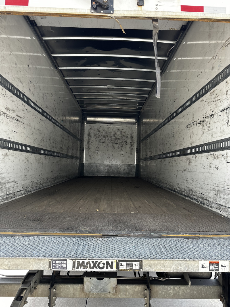 Freightliner M2-106 empty box truck trailer cargo area showing metal side rails and wooden floor.
