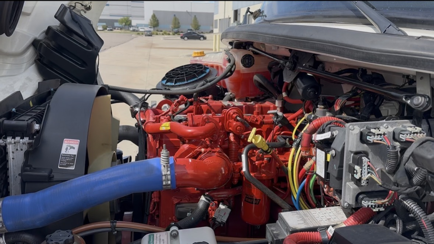 Freightliner M2-106 engine bay showing red turbo diesel engine with blue intercooler hose and various wiring harnesses