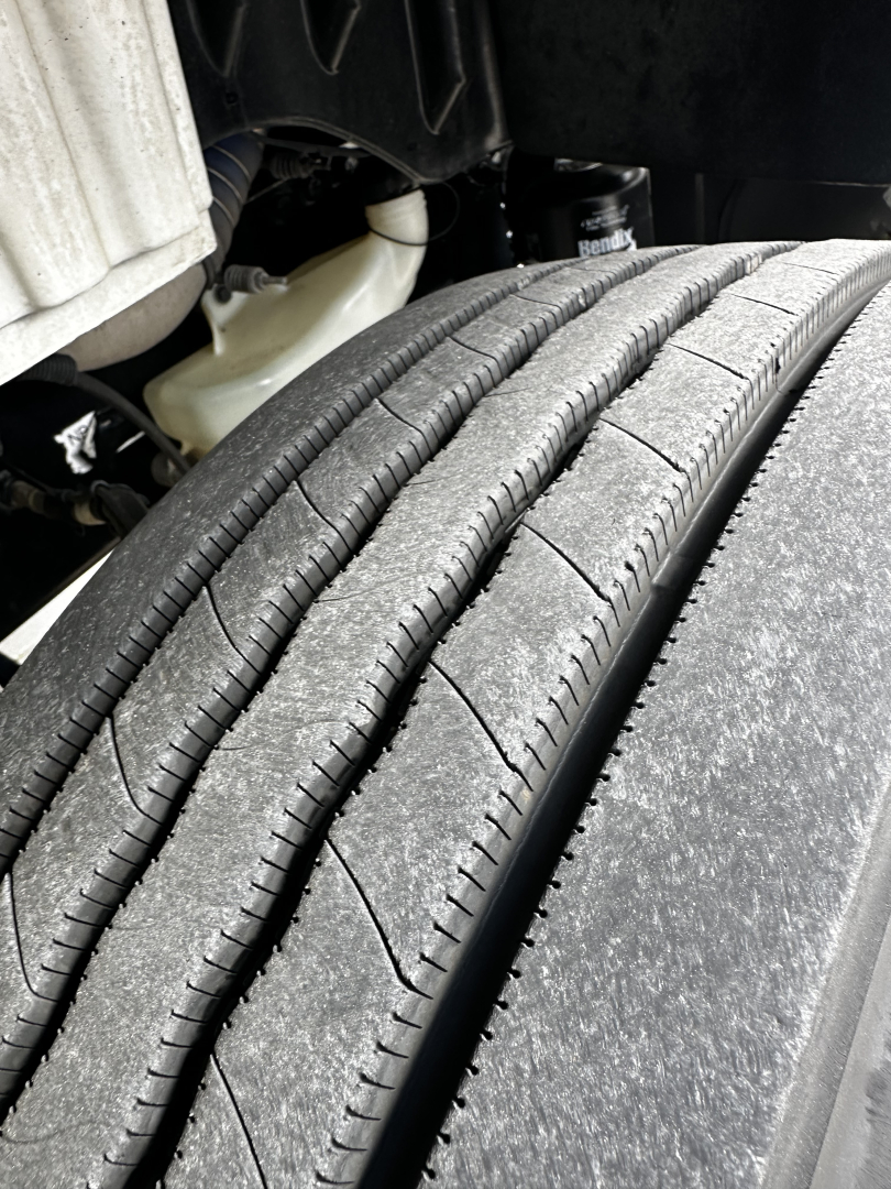Wheel/tires of a Freightliner M2-106 showing tread detail and suspension components.