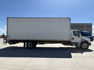 Freightliner M2-106 box truck side profile showing cargo box and cab with white exterior and blue sky.