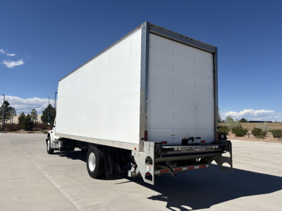 Freightliner M2-106 box truck rear and left side, white cargo box, rear underride guard, taillights, two rear doors; no visible text on the vehicle sides.